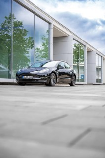 Black Tesla in front of a reflecting glass building on a cloudy day, Deer E-Carsharing, Tesla Model