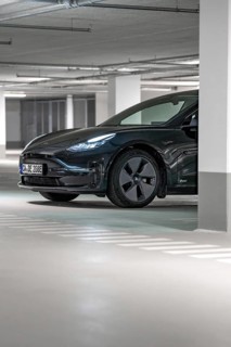 Black Tesla in parking garage, partly hidden by pillar, illuminated, Deer E-Carsharing, Tesla Model