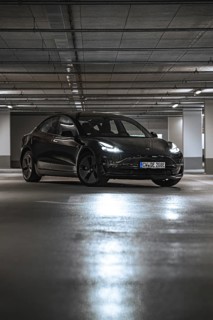 Black car in a parking garage with reflecting lights on the ground, Deer E-Carsharing, Tesla Model