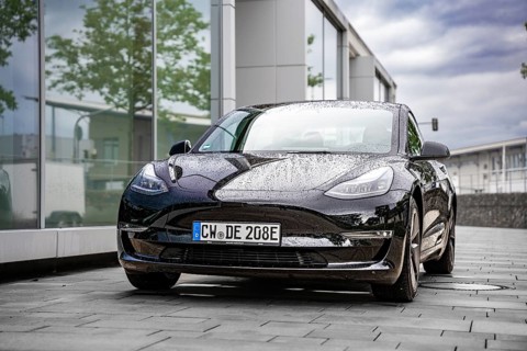 Wet Tesla in front of a modern glass building, covered with raindrops, Deer E-Carsharing, Tesla
