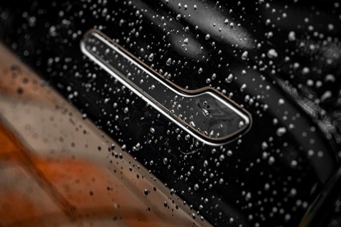 Close-up of a black car with water droplets on the surface showing shiny details, Deer E- car