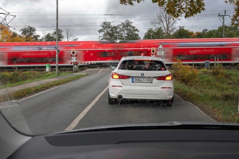 Regional train crosses a restricted level crossing, cars waiting in front of it, Fürth