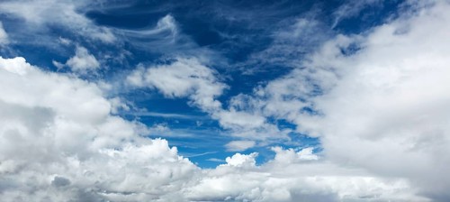 A peaceful sky filled with soft clouds creates a calming atmosphere under the bright sun of a clear