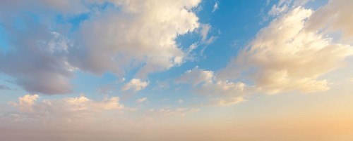 Colorful sunset sky showcases vibrant hues and fluffy clouds as day transitions into night,