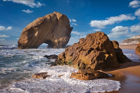 Penedo do Guincho stands majestically at Praia da Santa Cruz, surrounded by ocean waves as the sun