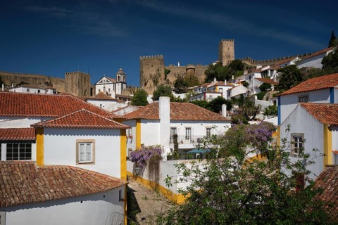 Discover the beauty of Obidos, Portugal, with its medieval castle and charming white houses beneath