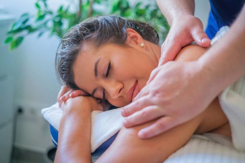 A woman enjoys a soothing back massage by a professional therapist using oil in a serene spa salon