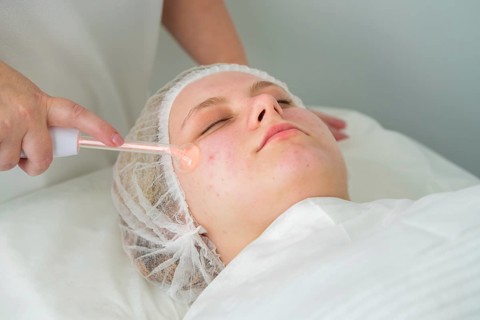 Client receives Darsonvalization treatment with a glass electrode to enhance skin healing and