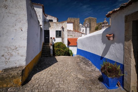 Historic streets of Obidos, Portugal, surrounded by white houses and stone walls under a clear blue