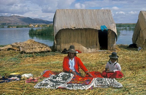 Mother and little daughter sell souvenirs on a floating Uro island in Lake Titcaca, Andean