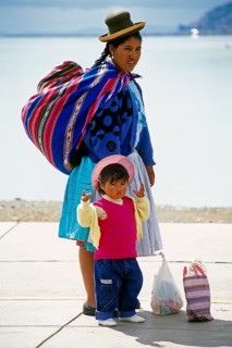 Traditionally dressed young woman with young daughter at Lake Titicaca in Puno, Andean Highlands,