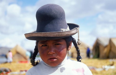Little girl in traditional clothing on a floating Uro island in Lake Titcaca, Andean highlands,