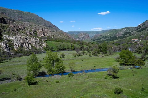 Extensive green valley with a small river and hill background. Peaceful natural landscape, Kura