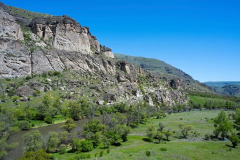 A river flows through a green valley with rocky slopes and trees, Kura River, landscape near