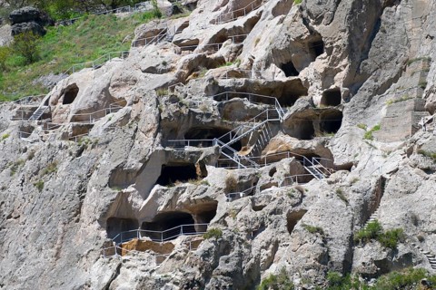 Nested monastery in rocks with caves and balustrades. Historical stone architecture, cave town,