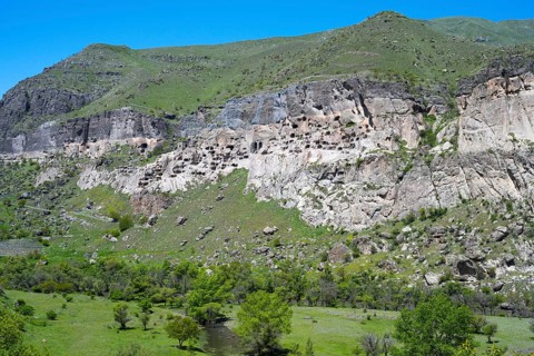 A rocky cliff with numerous caves carved into the rock face, cave town, cave monastery, Kura River,