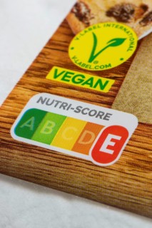 Food label with Nutri-Score E and vegan seal on wooden surface
