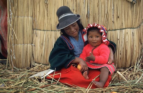 Children sitting in front of a reed hut on a floating Uro island in Lake Titcaca, Peru, South