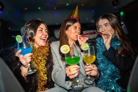 Young women friends celebrating a new year's eve or special occasion, having fun in a car, enjoying