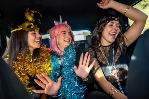 Young women friends celebrating a joyful costume party inside a car, expressing happiness and fun