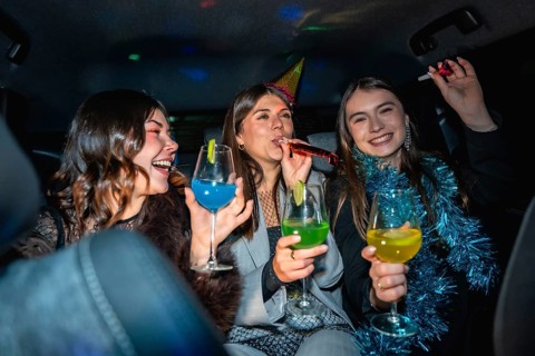 Three happy young women friends celebrating a cheerful new year's eve party in a vehicle, enjoying