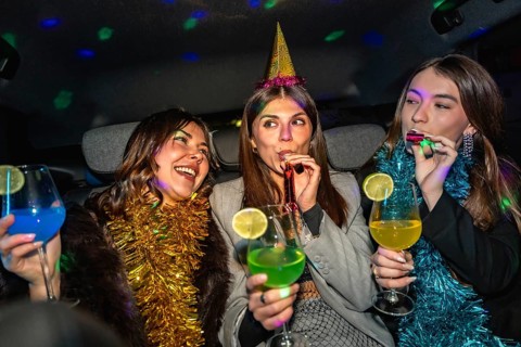 Young women celebrating a festive night out in a decorated party car with disco lights, tinsel and