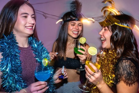 Diverse group of young women celebrating a new year's eve party or costume event, laughing and