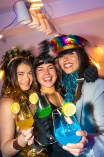 Three happy young women celebrating new year's eve, wearing festive costumes and holding colorful