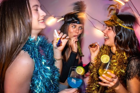 Three happy young women enjoying a lively new year's eve or costume party, wearing festive