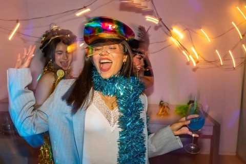 Three cheerful young women dancing and laughing together at a vibrant new year's eve or costume
