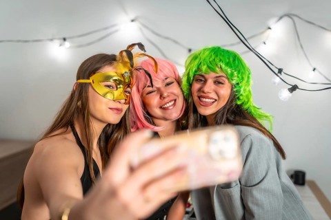 Group of happy young women celebrating new year's eve or a costume party indoors, smiling and