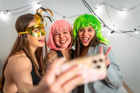 Girls friends celebrating a new year's eve or costume party, laughing and taking a selfie with a