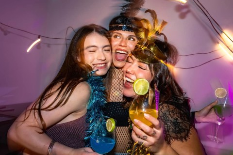Three happy young women embracing, laughing and enjoying a festive celebration filled with
