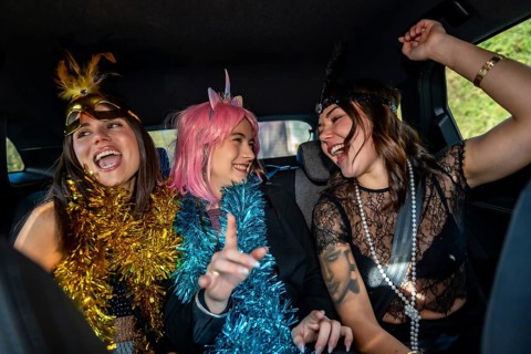 Young happy women dressed in costumes and festive garlands celebrating, laughing, and having fun