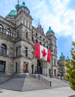 Parliament buildings in victoria, british columbia, proudly displaying a large canadian flag,