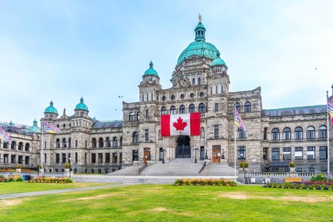 British columbia parliament buildings with large canadian flag hanging from the front during a