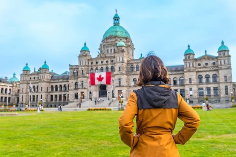 Tourist standing in front of the impressive parliament buildings, proudly displaying the canadian