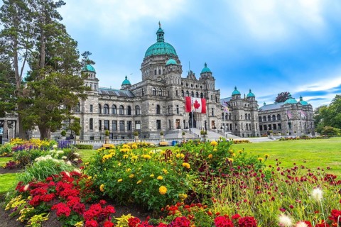 Canadian flag waving in front of parliament buildings in victoria, british columbia, canada during