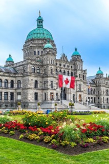 Canadian flag waving proudly in front of the british columbia parliament buildings in victoria,