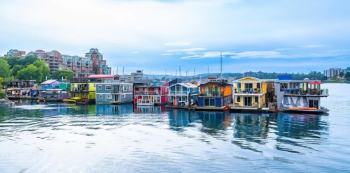 Colorful floating homes at fisherman's wharf park are reflecting in the calm water in victoria,