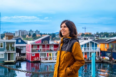 Happy tourist admiring the colorful floating houses of fisherman's wharf park in victoria, british