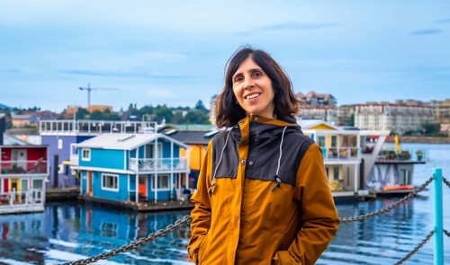 Happy tourist smiling brightly with vibrant floating houses lining the harbor in the background on