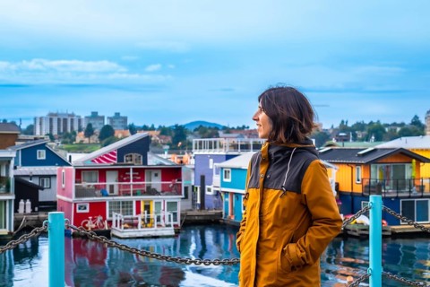 Young woman tourist admiring the colorful floating houses of fisherman's wharf park in victoria,