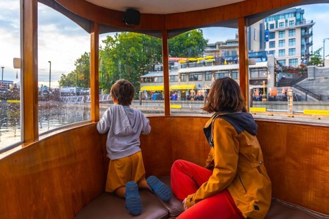 Mother and son are enjoying a harbor tour of victoria, british columbia, taking in the sights of