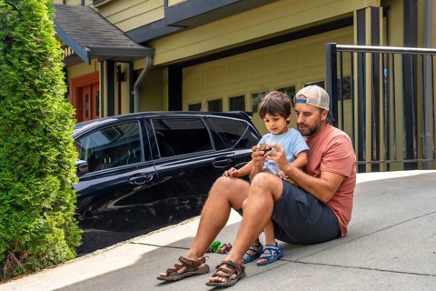 Father and son bonding while playing with a toy car on the driveway, sharing joyful moments