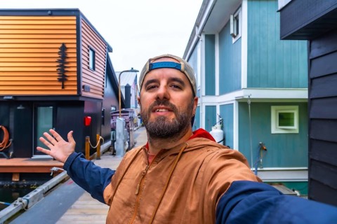 Tourist taking a selfie and showing with his hand floating houses in fishermans wharf park,