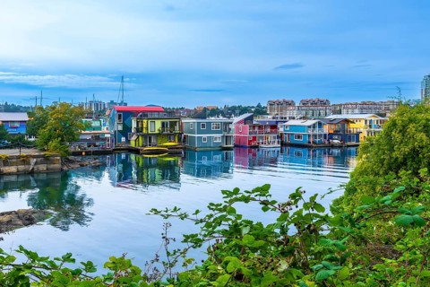 Colorful floating homes reflecting in the calm water at fisherman's wharf park in victoria, british
