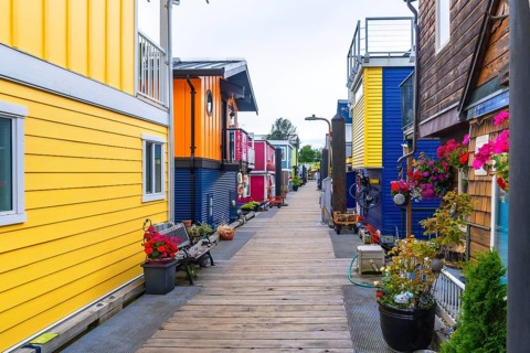 Wooden pathway leading through fisherman's wharf park, featuring vibrant floating homes, potted