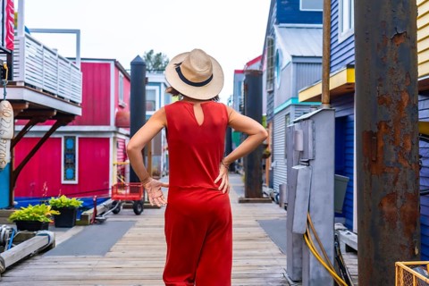 Tourist wearing a red jumpsuit and straw hat walking at fisherman's wharf park, a colorful floating