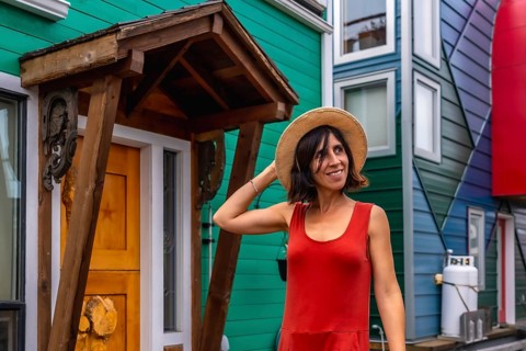 Smiling tourist holding her straw hat while visiting the colorful houses in the fisherman's wharf
